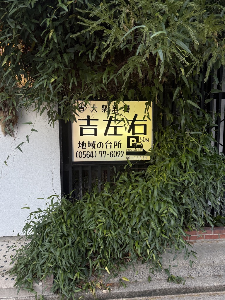 店の前の黄色い看板。大衆酒場 吉左右、地域の台所、電話番号、駐車場50m・6台の案内